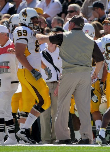 BOULDER, CO - SEPTEMBER 19:  Head coach Dave Christensen of the Wyoming Cowboys grabs right tackle John Hutchins #69 as he comes off the field and has words for him after he was called for illegal motion against the Colorado Buffaloes at Folsom Field on September 19, 2009 in Boulder, Colorado.  <br /><br /><span class="help">(Photo by Doug Pensinger/Getty Images)</span>