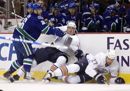 VANCOUVER, CANADA - SEPTEMBER 19: Jannik Hansen #36 of the Vancouver Canucks knocks down Bryan Young #28 and Dustin Penner #27 of the Edmonton Oilers along the boards during the first period of NHL preseason action on September 19, 2009 at General Motors Place in Vancouver, British Columbia, Canada.  <br /><br /><span class="help">(Photo by Rich Lam/Getty Images)</span>
