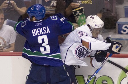 VANCOUVER, CANADA - SEPTEMBER 19: Denis Grebeshkov #37 of the Edmonton Oilers evades a hit delivered by Kevin Bieksa #3 of the Vancouver Canucks during the second period of NHL preseason action on September 19, 2009 at General Motors Place in Vancouver, British Columbia, Canada.  <br /><br /><span class="help">(Photo by Rich Lam/Getty Images)</span>
