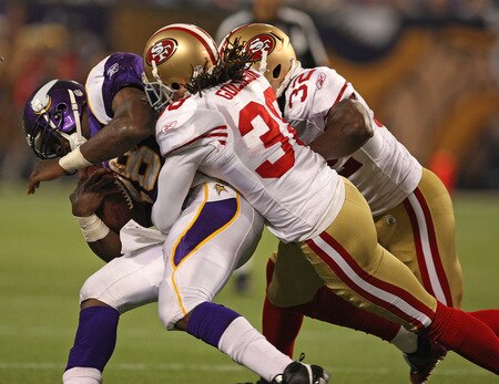 MINNEAPOLIS - SEPTEMBER 27: Adrian Peterson #28 of the Minnesota Vikings is pulled down by Dashon Goldson #38 and Michael Lewis #32 of the San Francisco 49ers at the Hubert H. Humphrey Metrodome on September 27, 2009 in Minneapolis, Minnesota. The Vikings defeated the 49ers 27-24. <br /><br /><span class="help">(Photo by Jonathan Daniel/Getty Images)</span>