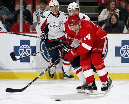 DETROIT - OCTOBER 10: Derek Meech #14 of the Detroit Red Wings tries to control the puck in front of Matt Bradley #10 of the Washington Capitals on October 10, 2009 at Joe Louis Arena in Detroit, Michigan. <br /><br /><span class="help">(Photo by Gregory Shamus/Getty Images)</span>