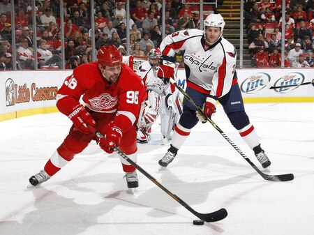 DETROIT - OCTOBER 10: Tomas Holmstrom #96 of the Detroit Red Wings battles for the puck with Tom Poti #3 of the Washington Capitals on October 10, 2009 at Joe Louis Arena in Detroit, Michigan. <br /><br /><span class="help">(Photo by Gregory Shamus/Getty Images)</span>