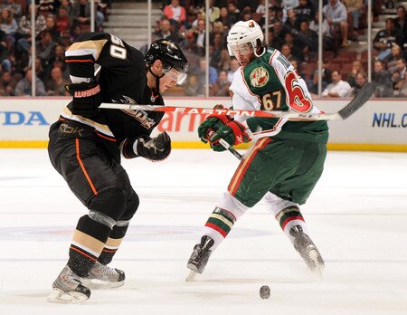 ANAHEIM, CA - OCTOBER 14:  Brendan Mikkelson #60 of the Anaheim Ducks attempts to control the puck in front of Benoit Pouliot #67 of the Minnesota Wild during the second period at the Honda Center on October 14, 2009 in Anaheim, California.  <br /><br /><span class="help">(Photo by Harry How/Getty Images)</span>