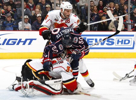 COLUMBUS, OH - OCTOBER 13: Miikka Kiprusoff #34 of the Calgary Flames holds the puck while teammate Robyn Regehr #28 checks Antoine Vermette #50 of the Columbus Blue Jackets into him on October 13, 2009 at Nationwide Arena in Columbus, Ohio.  <br /><br /><span class="help">(Photo by Gregory Shamus/Getty Images)</span>