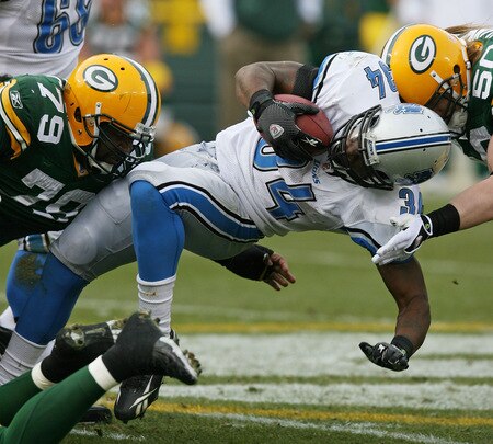 GREEN BAY, WI - OCTOBER 18:  Kevin Smith #34 of the Detroit Lions is tackled by Ryan Pickett #79 and A.J. Hawk #50 of the Green Bay Packers at Lambeau Field on October 18, 2009 in Green Bay, Wisconsin. The Packers defeated the Lions 26-0. <br /><br /><span class="help">(Photo by Jonathan Daniel/Getty Images)</span>