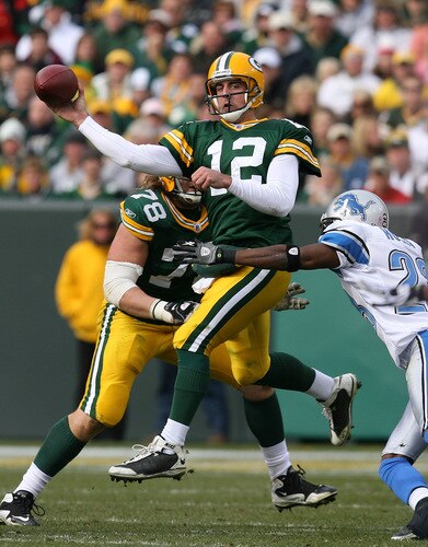 GREEN BAY, WI - OCTOBER 18: Aaron Rodgers #12 of the Green Bay Packers leaps to throw a pass under pressure from Kevin Hobbs #23 of the Detroit Lions at Lambeau Field on October 18, 2009 in Green Bay, Wisconsin. The Packers defeated the Lions 26-0.  <br /><br /><span class="help">(Photo by Jonathan Daniel/Getty Images)</span>