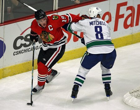 CHICAGO - OCTOBER 21: Jonathan Toews #19 of the Chicago Blackhawks moves the puck around Willie Mitchell #8 of the Vancouver Canucks at the United Center on October 14, 2009 in Chicago, Illinois. <br /><br /><span class="help">(Photo by Jonathan Daniel/Getty Images)</span>