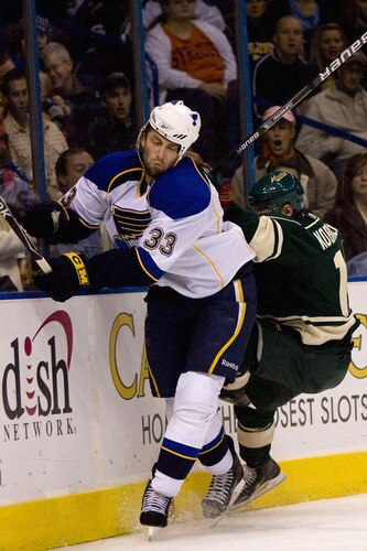 ST. LOUIS, MO. - OCTOBER 23: Tyson Strachan #33 of the St. Louis Blues is checked into the boards by Chuck Kobasaew #12 of the Minnesota Wild at the Scottrade Center on October 23, 2009 in St. Louis, Missouri.  <br /><br /><span class="help">(Photo by Dilip Vishwanat/Getty Images)</span>