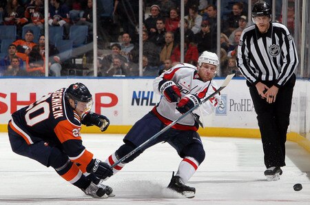 UNIONDALE, NY - JANUARY 26:  Karl Alzner #27 of the Washington Capitals dumps the puck past Sean Bergenheim #20 of the New York Islanders on January 26, 2010 at Nassau Coliseum in Uniondale, New York.  <br /><br /><span class="help">(Photo by Jim McIsaac/Getty Images)</span>