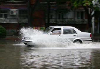BEIJING, CHINA - AUGUST 10: (CHINA OUT) A car drives through water on a flooded road after heavy rain on August 10, 2008 in Beijing, China. Heavy rain has cooled the city down to about 26 degrees Centigrade today, but also delayed the Olympic tennis competition for about an hour, on the second day of the Olympics. (Photo by China Photos/Getty Images)