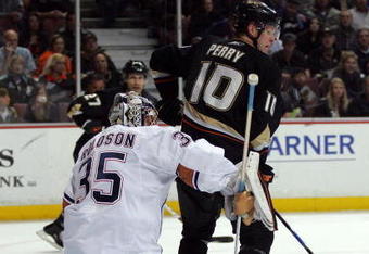 ANAHEIM, CA - MARCH 27:  Corey Perry #10 of the Anaheim Ducks sets a screen as goaltender Dwayne Roloson #35 of the Edmonton Oilers makes a blocker save during the NHL game at Honda Center on March 27, 2009 in Anaheim, California. The Oilers defeated the Ducks 5-3. (Photo by Victor Decolongon/Getty Images)