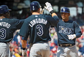 PHILADELPHIA - APRIL 4: First baseman Carlos Pena #23 of the Tampa Bay Rays gets congratulated by teammates left fielder Carl Crawford #13 and third baseman Evan Longoria #3 after hitting a 3 run home-run in the top of the first inning during the game against the Philadelphia Phillies on April 4, 2009 at Citizens Bank Park in Philadelphia, Pennsylvania.  The Rays won 9-7. (Photo by Drew Hallowell/Getty Images)