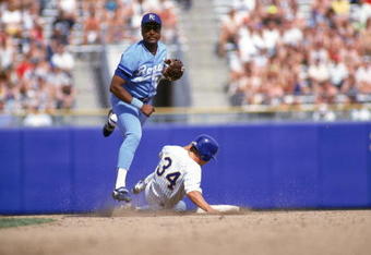 1990:  Frank White #20 of the Kansas City Royals tries to turn a double play as he throws to first base after forcing out the sliding runner at second base during a game in 1990.  (Photo by Otto Greule Jr/Getty Images)