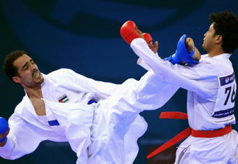 DOHA, QATAR - DECEMBER 13:  Kushal Shresta (R) of Nepal receives a kick to the face from Fadi Al Najjar (L) of Jordan during the Men's Karate 65kg preliminary round match during the 15th Asian Games Doha 2006 at The Qatar Sports Club Indoor Hall, Dedcember13, 2006 in Doha, Qatar.  (Photo by Jamie Squire/Getty Images)