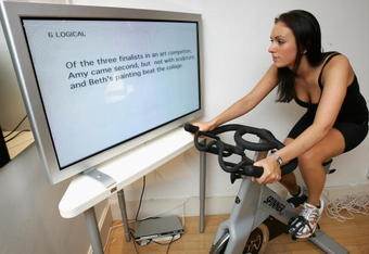 LONDON - JULY 18: A woman exercises in front of a screen displaying puzzles and games as part of a full mind and body workout at the Fit Rooms on July 18, 2007 in London, England. Newly launched 'Puzzler Brain Train' Magazine has teamed up with the Fit Rooms in Fulham so that gym-goers can muscle up their brain power for National Brain Train Awareness Week, July 16-22.  (Photo by Chris Jackson/Getty Images)