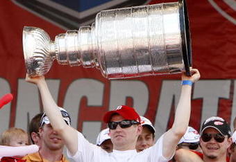 DETROIT - JUNE 06:  Chris Osgood #30 of the Detroit Red Wings holds up the Stanley Cup during a rally to celebrate winning the 2008 Stanley Cup on June 6, 2008 in Detroit, Michigan.  (Photo by Gregory Shamus/Getty Images)