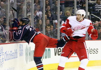 COLUMBUS, OH - APRIL 23:  Manny Malhotra #27 of the Columbus Blue Jackets is hammered into the boards by Brad Stuart #23 of the Detroit Red Wings during Game Four of the Western Conference Quarterfinals of the 2009 Stanley Cup Playoffs on April 23, 2009 at the Nationwide Arena in Columbus, Ohio. The Red Wings defeated the Blue Jackets 6-5 to sweep the series in 4 games. (Photo by Claus Andersen/Getty Images)