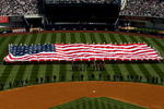 NEW YORK - APRIL 16:  Recording artist Kelly Clarkson sings the National Anthem as members of the military hold a giant American flag before the opening day game between the Cleveland Indians and the New York Yankees at the new Yankee Stadium on April 16, 2009 in the Bronx borough of New York City. This is the first regular season MLB game being played at the new venue which replaced the old Yankee Stadium as the Yankees home field.  (Photo by Nick Laham/Getty Images)
