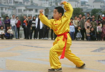 JIANGMEN, CHINA - FEBRUARY 15: A young member of 'Choy Lay Fut' lion dance group performs Kung Fu at a residential district on Febuary 15, 2005 in Jiangmen, Guangdong Province, China. The lion dance, which brings good luck to households or business visited by the lion, is a traditional part of the celebration for the Chinese New Year and is performed by two people- one at the head and one at the tail. Chinese lion dancing has been a popular form of martial art in China since its origin in approximately 400 B.C. (Photo by Cancan Chu/GettyImages)