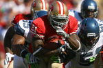 SAN FRANCISCO - OCTOBER 26:  Runningback Frank Gore #21 of the San Francisco 49ers carries the ball while being pursued by Lawrence Jackson #95 of the Seattle Seahawks in the first quarter at Candlestick Park on October 26, 2008 in San Francisco, California. The Seahawks defeated the 49ers 34-13.  (Photo by Jeff Gross/Getty Images)