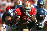 SAN FRANCISCO - OCTOBER 26:  Runningback Frank Gore #21 of the San Francisco 49ers carries the ball while being pursued by Lawrence Jackson #95 of the Seattle Seahawks in the first quarter at Candlestick Park on October 26, 2008 in San Francisco, California. The Seahawks defeated the 49ers 34-13.  (Photo by Jeff Gross/Getty Images)