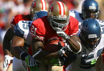 SAN FRANCISCO - OCTOBER 26:  Runningback Frank Gore #21 of the San Francisco 49ers carries the ball while being pursued by Lawrence Jackson #95 of the Seattle Seahawks in the first quarter at Candlestick Park on October 26, 2008 in San Francisco, California. The Seahawks defeated the 49ers 34-13.  (Photo by Jeff Gross/Getty Images)