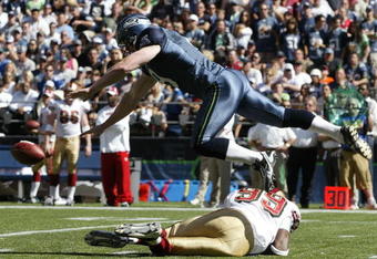 SEATTLE - SEPTEMBER 14:  Punter Jon Ryan #9 of the Seattle Seahawks tumbles over Manny Lawson #99 of the San Francisco 49ers after Lawson ran into Ryan on a blocked punt on September 14, 2008 at Qwest Field in Seattle Washington. The 49ers defeated the Seahawks 33-30 in overtime. (Photo by Otto Greule Jr/Getty Images)