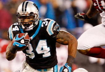 CHARLOTTE, NC - JANUARY 10:  DeAngelo Williams #34 of the Carolina Panthers runs the ball while Bryan Robinson #97 of the Arizona Cardinals looks on during the NFC Divisional Playoff Game on January 10, 2009 at Bank of America Stadium in Charlotte, North Carolina.  (Photo by Streeter Lecka/Getty Images)