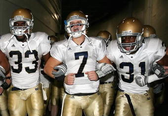 LOS ANGELES, CA - NOVEMBER 29:  Quarterback Jimmy Clausen #7 of the Notre Dame Fighting Irish walks out with teammates Robert Hughes #33 and Sergio Brown #31 before the game against the USC Trojans at Los Angeles Memorial Coliseum on November 29, 2008 in Los Angeles, California. The Trojans defeated the Fighting Irish 38-3.  (Photo by Christian Petersen/Getty Images)