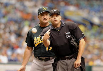 ST PETERSBURG, FL - JULY 23: Home plate umpire Andy Fletcher tosses a ball but not manager Bob Geren of the Oakland Athletics during an argument in a game against the Tampa Rays July 23, 2008 at Tropicana Field in St. Petersburg, Florida.  (Photo by Al Messerschmidt/Getty Images)
