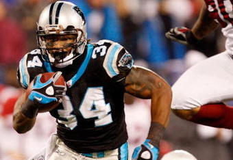 CHARLOTTE, NC - JANUARY 10:  DeAngelo Williams #34 of the Carolina Panthers runs the ball while Bryan Robinson #97 of the Arizona Cardinals looks on during the NFC Divisional Playoff Game on January 10, 2009 at Bank of America Stadium in Charlotte, North Carolina.  (Photo by Streeter Lecka/Getty Images)