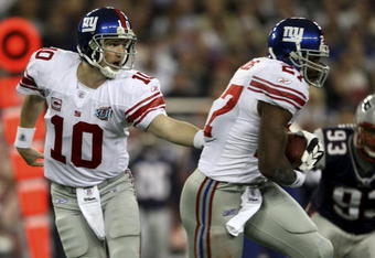 GLENDALE, AZ - FEBRUARY 03:  Quarterback Eli Manning #10 of the New York Giants hands the football off to running back Brandon Jacobs #27 during the first drive in the first quarter against the New England Patriots in Super Bowl XLII on February 3, 2008 at the University of Phoenix Stadium in Glendale, Arizona.  (Photo by Elsa/Getty Images)