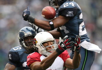 SEATTLE - DECEMBER 9:  Wide receiver Larry Fitzgerald #11 of the Arizona Cardinals fights to make a catch against Deon Grant #24 of the Seattle Seahawks at Qwest Field December 9, 2007 in Seattle, Washington. The ball fell incomplete. (Photo by Otto Greule Jr/Getty Images)