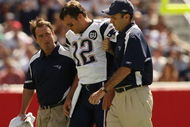 FOXBORO, MA - SEPTEMBER 7:  Quarterback Tom Brady #12 of the New England Patriots is helped off the field by trainers after he sustained an injury to his left knee in the first quarter against the Kansas City Chiefs at Gillette Stadium September 7, 2008 in Foxboro, Massachusetts.  (Photo by Elsa/Getty Images)