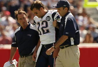 FOXBORO, MA - SEPTEMBER 7:  Quarterback Tom Brady #12 of the New England Patriots is helped off the field by trainers after he sustained an injury to his left knee in the first quarter against the Kansas City Chiefs at Gillette Stadium September 7, 2008 in Foxboro, Massachusetts.  (Photo by Elsa/Getty Images)