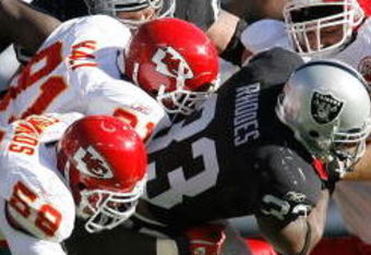 OAKLAND - October 21:  Running back Dominic Rhodes #33 of the Oakland Raiders is gang tackled by linebacker Donnie Edwards #59 and defensive linemen Tamba Hali #91 and Jared Allen #69 of the Kansas City Chiefs during a game at McAfee Coliseum October 21, 2007 in Oakland, California. California. Kansas City won 12-10.  (Photo by Greg Trott/Getty Images)