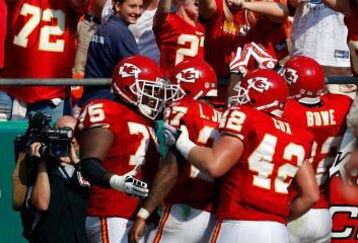 KANSAS CITY, MO - SEPTEMBER 28:  Fans cheer as teammates congratulate Larry Johnson #27 of the Kansas City Chiefs after Johnson rushed for a touchdown during the fourth quarter of the game against the Denver Broncos on September 28, 2008 at Arrowhead Stadium in Kansas City, Missouri.  (Photo by Jamie Squire/Getty Images)