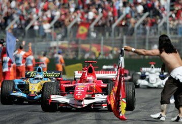 IMOLA, ITALY - APRIL 23:  Michael Schumacher of Germany and Ferrari celebrates winning the San Marino Formula One Grand Prix as he enters the pitlane in front of Fernando Alonso of Spain and Renault at the San Marino Circuit on April 23, 2006, in Imola, Italy.  (Photo by Paul Gilham/Getty Images)