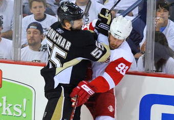 PITTSBURGH - JUNE 09:  Johan Franzen #93 of the Detroit Red Wings is checked into the boards by Sergei Gonchar #55 of the Pittsburgh Penguins during Game Six of the NHL Stanley Cup Finals at the Mellon Arena on June 9, 2009 in Pittsburgh, Pennsylvania.  (Photo by Jamie Sabau/Getty Images)