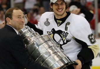DETROIT - JUNE 12:  NHL commissioner Gary Bettman presents Sidney Crosby #87 of the Pittsburgh Penguins with the Stanley Cup after his team defeated the Detroit Red Wings by a score of 2-1 to win Game Seven and the 2009 NHL Stanley Cup Finals at Joe Louis Arena on June 12, 2009 in Detroit, Michigan.  (Photo by Bruce Bennett/Getty Images)