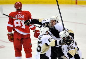 DETROIT - JUNE 12:  Maxime Talbot #25 of the Pittsburgh Penguins celebrates his first goal in the second period with teammates Evgeni Malkin #71 and Ruslan Fedotenko #26 as Marian Hossa #81 of the Detroit Red Wings skates by during Game Seven of the 2009 NHL Stanley Cup Finals at Joe Louis Arena on June 12, 2009 in Detroit, Michigan.  (Photo by Jamie Sabau/Getty Images)