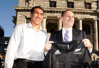 WELLINGTON, NEW ZEALAND - JUNE 15:  New Zealand Prime Minister John Key (R) receives a signed New Zealand All Blacks jersey from captain Mils Muliaina following an All Blacks flag raising ceremony at the New Zealand Parliament Building on June 15, 2009 in Wellington, New Zealand. The All Blacks are in Wellington to play France in the second test of their two match series, having lost the first 27-22.  (Photo by Ross Land/Getty Images)