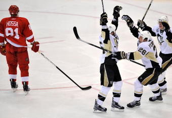 DETROIT - JUNE 12:  Maxime Talbot #25 of the Pittsburgh Penguins celebrates his first goal in the second period with teammates Evgeni Malkin #71 and Ruslan Fedotenko #26 as Marian Hossa #81 of the Detroit Red Wings skates by during Game Seven of the 2009 NHL Stanley Cup Finals at Joe Louis Arena on June 12, 2009 in Detroit, Michigan.  (Photo by Jamie Sabau/Getty Images)