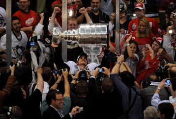 DETROIT - JUNE 12:  Sidney Crosby #87 of the Pittsburgh Penguins hoists the Stanley Cup overhead in the midst of fans and photographers after Game Seven of the 2009 NHL Stanley Cup Finals against the Detroit Red Wings at Joe Louis Arena on June 12, 2009 in Detroit, Michigan. The Penguins defeated the Red Wings 2-1 in the seventh game to win the Stanley Cup Finals series 4 games to 3. (Photo by Harry How/Getty Images)