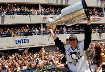 PITTSBURGH - JUNE 15:  Sidney Crosby #87 of the Pittsburgh Penguins holds the Stanley Cup aloft for the fans along the Blvd of the Allies during the Stanley Cup Champion Victory Parade on June 15, 2009 in Pittsburgh, Pennsylvania.  (Photo by Jamie Sabau/Getty Images)