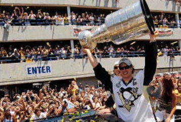 PITTSBURGH - JUNE 15:  Sidney Crosby #87 of the Pittsburgh Penguins holds the Stanley Cup aloft for the fans along the Blvd of the Allies during the Stanley Cup Champion Victory Parade on June 15, 2009 in Pittsburgh, Pennsylvania.  (Photo by Jamie Sabau/Getty Images)