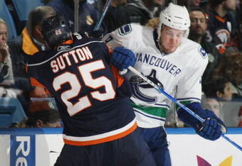 UNIONDALE, NY - NOVEMBER 17: Andy Sutton #25 of the New York Islanders hits Taylor Pyatt #9 of the Vancouver Canucks on November 17, 2008 at the Nassau Coliseum in Uniondale, New York. (Photo by Bruce Bennett/Getty Images)