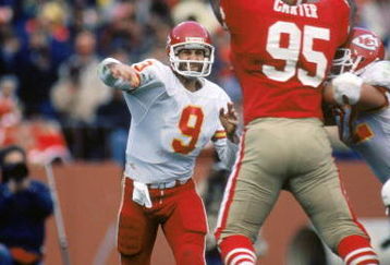 SAN FRANCISCO - NOVEMBER 17:  Quarterback Bill Kenney #9 of the Kansas City Chiefs attempts to pass over defensive linemen Michael Carter #95 of the San Francisco 49ers during a game at Candlestick Park on November 17, 1985 in San Francisco, California.  The 49ers won 31-3.  (Photo by George Rose/Getty Images)