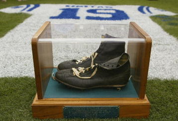 BALTIMORE - SEPTEMBER  15:  On display are the famous black high top shoes worn by Johnny Unitas while completing his last touchdown pass as a Colt on December 3, 1972.  A jersey painted with his name and uniform number on the grass is in the background.  The Baltimore Ravens paid tribute to Johnny Unitas prior to the start of the game against the Tampa Bay Buccaneers on September 15, 2002 at Ravens Stadium in Baltimore, Maryland.  The Baltimore Colts' Hall of Fame quarterback died of a heart attack September 11 at age 69.  The Buccaneers shut out the Ravens 25-0.  (Photo By Scott Halleran/Getty Images)