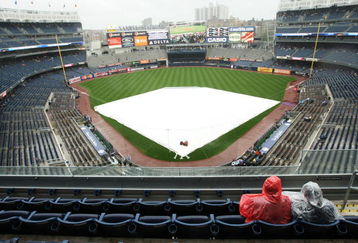 NEW YORK - JUNE 18:  Two fans sit during a rain delay before the game between the New York Yankees and the Washington Nationals on June 18, 2009 at Yankee Stadium in the Bronx Borough of New York City.  (Photo by Al Bello/Getty Images)